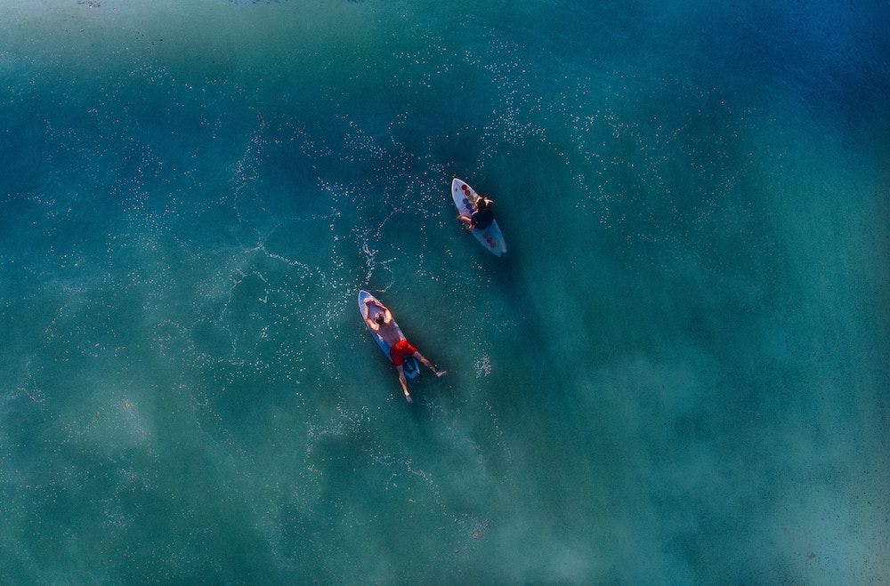 Birdview of two surfers on the open sea