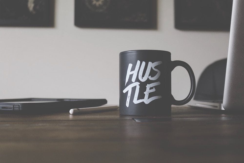 Mug with the HUSTLE message on an office table